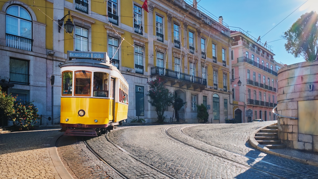 Yellow tram on a cobblestone street with classic buildings in the background in Lisbon, Portugal